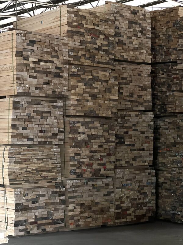 Stacks of raw wood materials stored in a factory warehouse before production