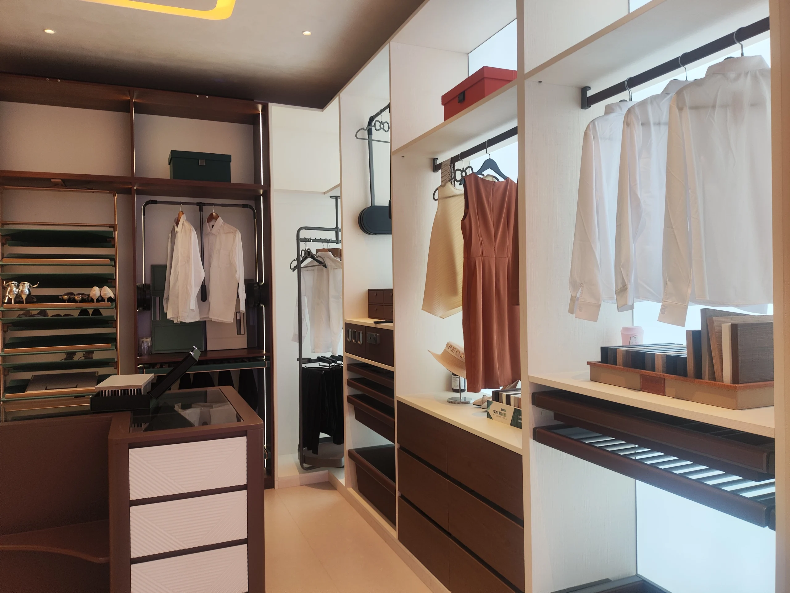 Custom wardrobe showroom with open hanging rails, built-in drawers, shelving, and dark wood finishes.
