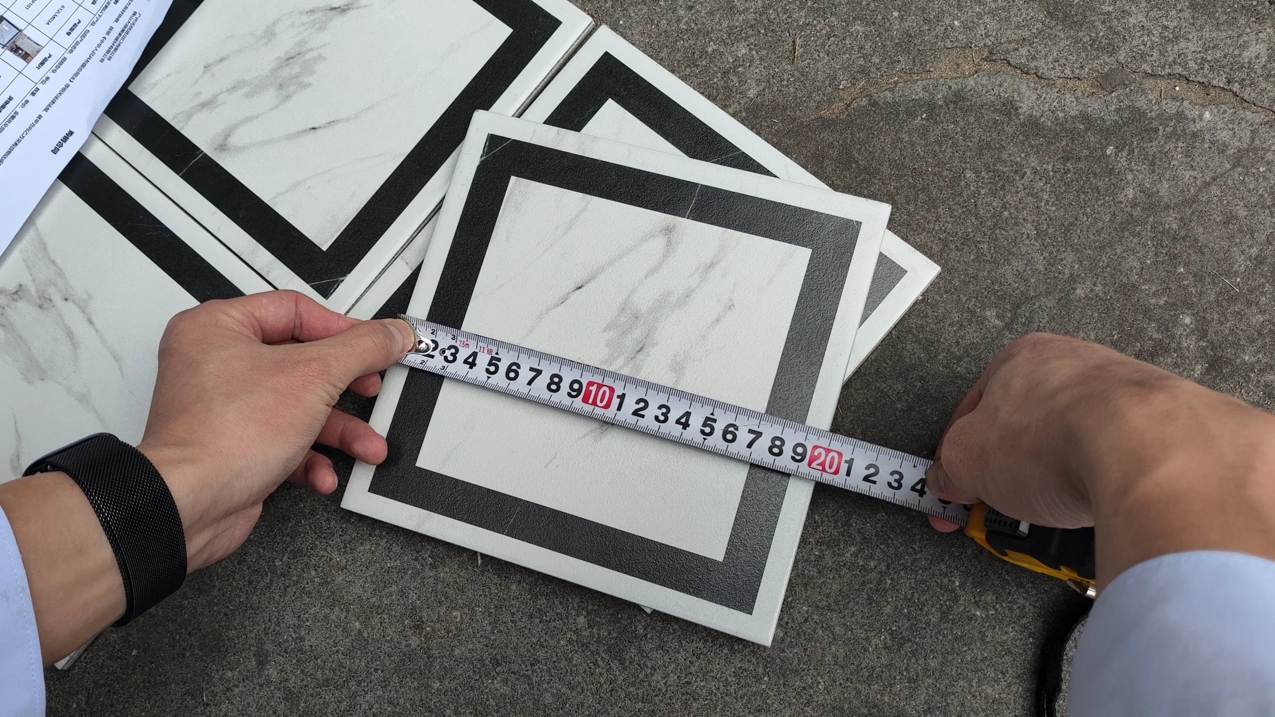 Tile Quality Control in China: How to Check Shade, Caliber, Flatness, Water Absorption and Packing 2 Measuring the dimensions of a marble-look tile sample with a tape measure during building material quality inspection in China.